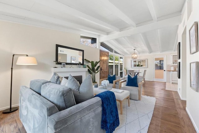 living room with hardwood / wood-style flooring, a fireplace, lofted ceiling with beams, and a notable chandelier