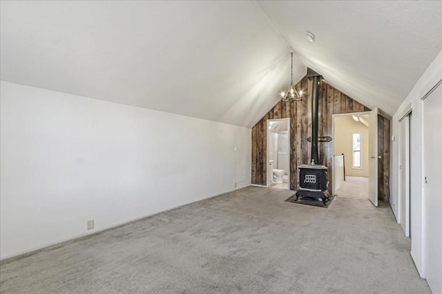 unfurnished living room with lofted ceiling, light carpet, and a wood stove