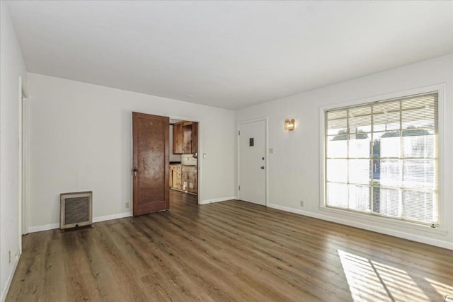 unfurnished room featuring dark hardwood / wood-style flooring and heating unit