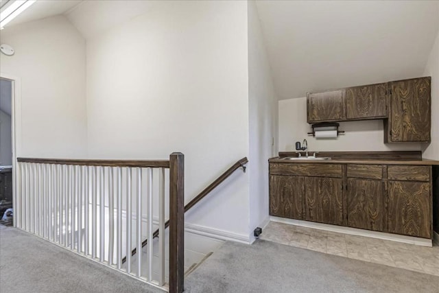 staircase featuring vaulted ceiling, carpet floors, and sink