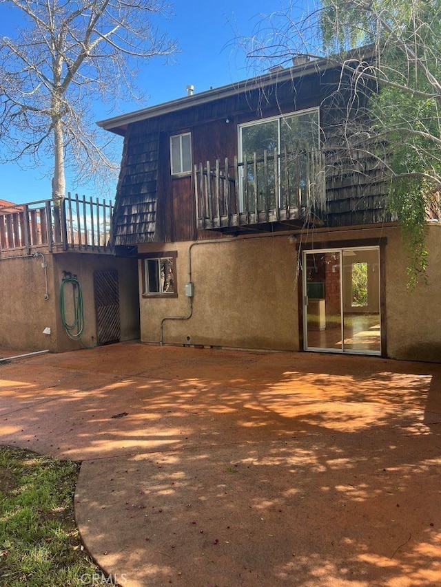 back of property featuring mansard roof and stucco siding