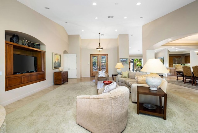 living room with french doors, light colored carpet, and a towering ceiling