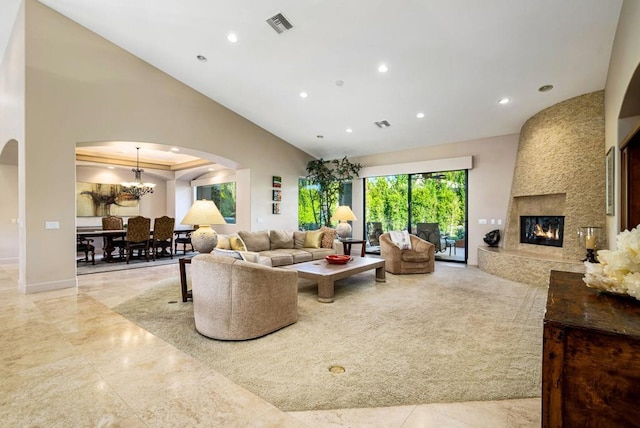 living room featuring high vaulted ceiling, an inviting chandelier, and a fireplace