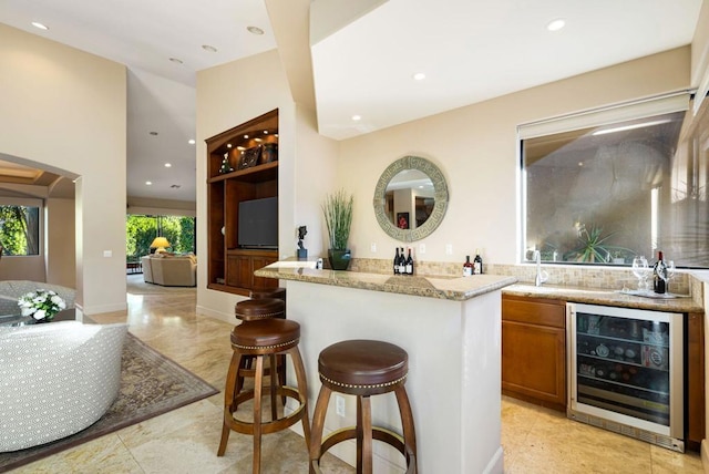 bar with light stone countertops and beverage cooler