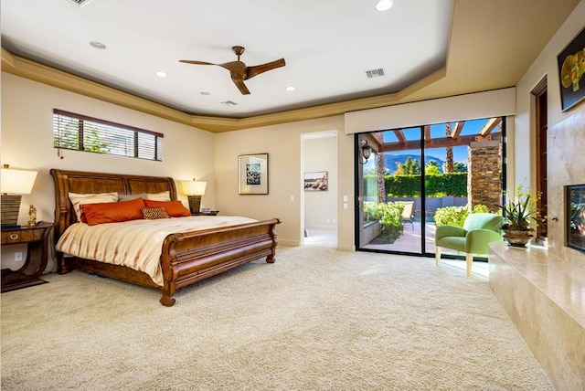 carpeted bedroom with a premium fireplace, access to outside, ceiling fan, and a tray ceiling