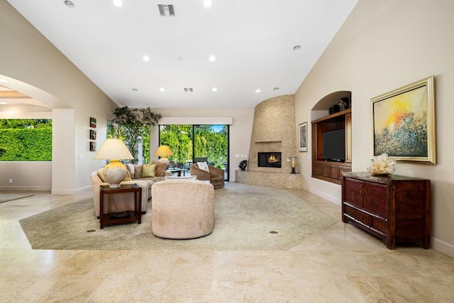 living room featuring a towering ceiling, built in features, and a fireplace