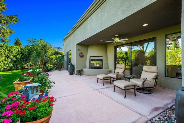 view of patio with ceiling fan and a fireplace