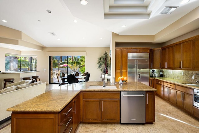 kitchen with tasteful backsplash, sink, an island with sink, and appliances with stainless steel finishes