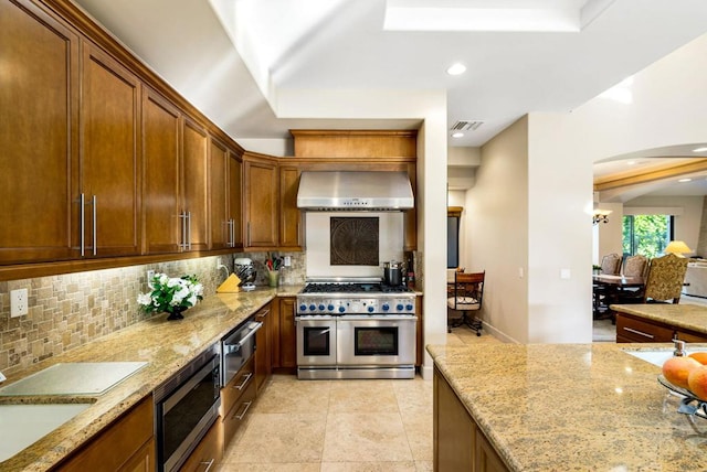 kitchen featuring appliances with stainless steel finishes, tasteful backsplash, sink, light stone countertops, and wall chimney exhaust hood