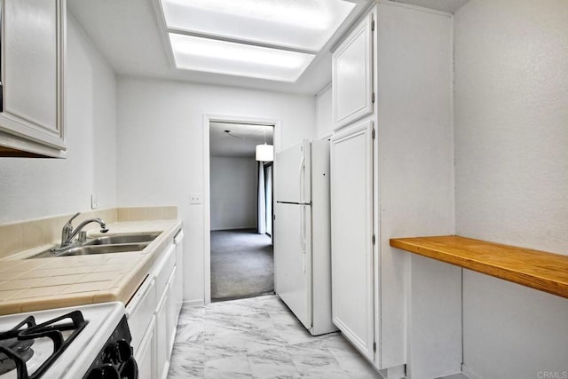 kitchen featuring range with gas cooktop, white cabinetry, sink, white fridge, and tile counters