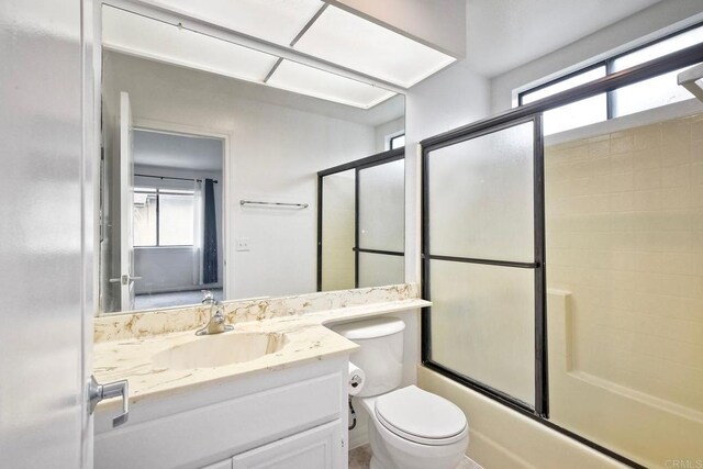 full bathroom with shower / bath combination with glass door, plenty of natural light, toilet, and vanity