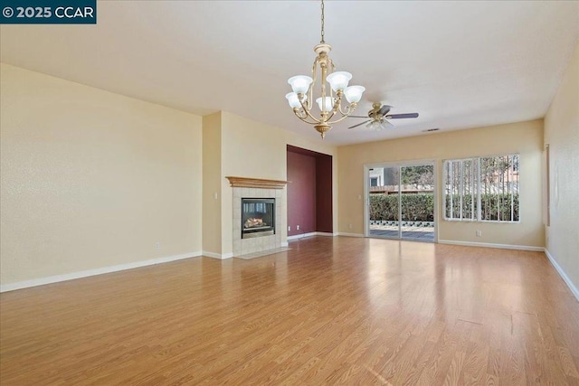 unfurnished living room featuring ceiling fan with notable chandelier, a fireplace, and light hardwood / wood-style flooring