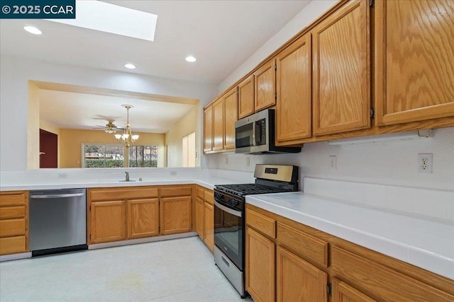 kitchen featuring a skylight, decorative light fixtures, sink, stainless steel appliances, and an inviting chandelier