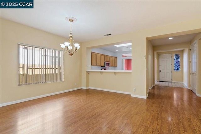 unfurnished living room featuring a notable chandelier and light wood-type flooring