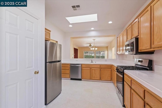 kitchen with appliances with stainless steel finishes, a skylight, sink, a chandelier, and hanging light fixtures