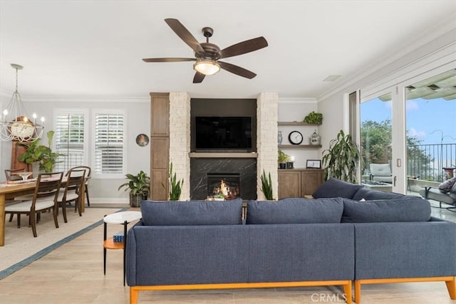 living room featuring a high end fireplace, crown molding, a wealth of natural light, and light hardwood / wood-style flooring