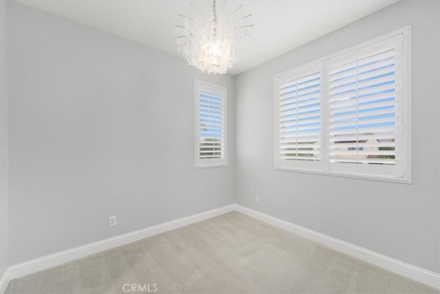 carpeted spare room featuring an inviting chandelier