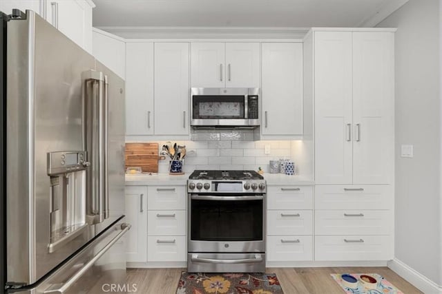 kitchen with appliances with stainless steel finishes, light hardwood / wood-style flooring, tasteful backsplash, and white cabinetry