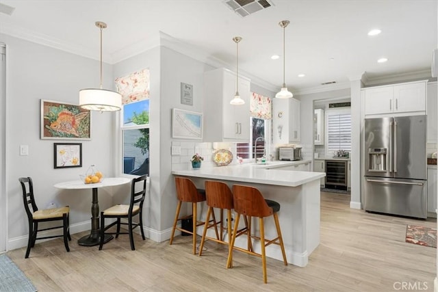 kitchen featuring white cabinetry, wine cooler, high quality fridge, kitchen peninsula, and tasteful backsplash