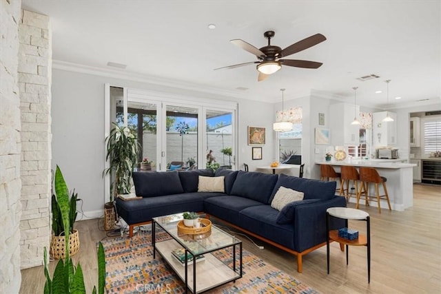 living room with ceiling fan, light wood-type flooring, crown molding, and beverage cooler