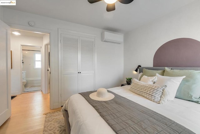 bedroom featuring ceiling fan, light hardwood / wood-style flooring, a closet, and a wall mounted AC