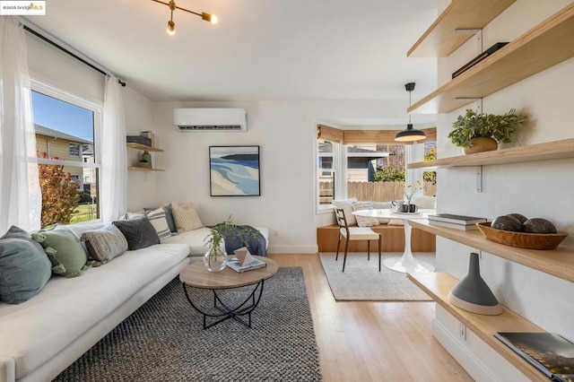 living room with an AC wall unit, a healthy amount of sunlight, and light wood-type flooring