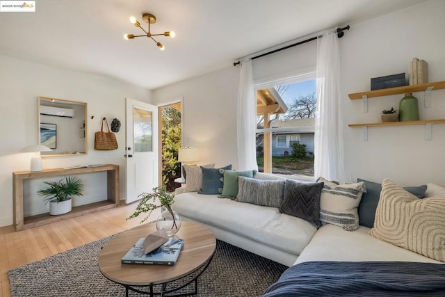 living room with an inviting chandelier, wood-type flooring, and a wall mounted air conditioner