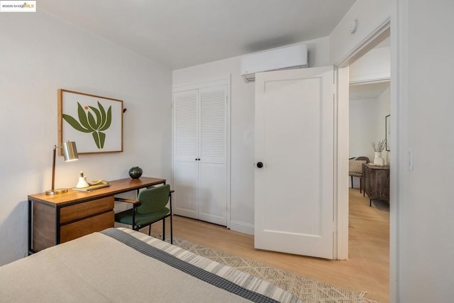 bedroom with a closet, a wall unit AC, and light hardwood / wood-style flooring