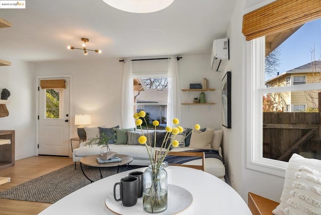 living room featuring an AC wall unit, a wealth of natural light, and light hardwood / wood-style flooring