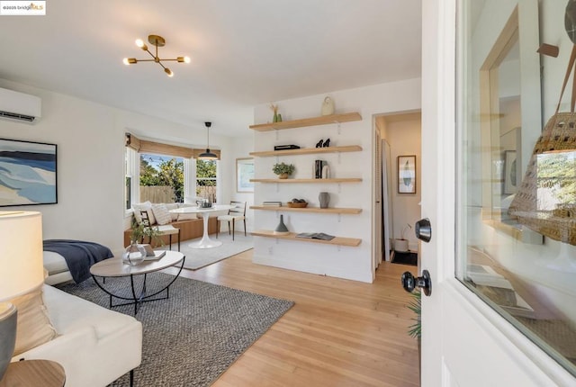 living room featuring an inviting chandelier, an AC wall unit, and light wood-type flooring