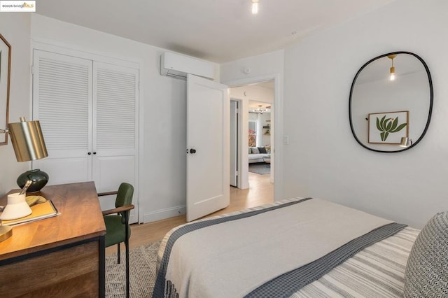 bedroom featuring a closet, light hardwood / wood-style flooring, and an AC wall unit