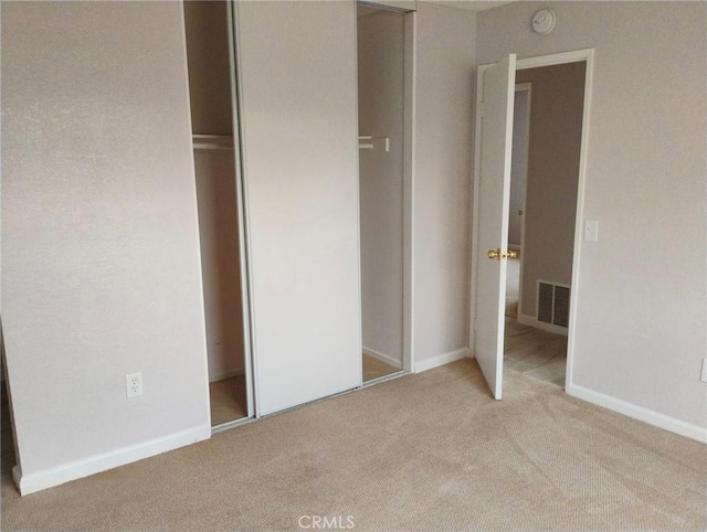 unfurnished bedroom with light colored carpet and a closet