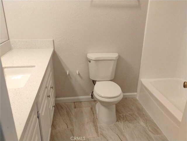 bathroom featuring vanity, a washtub, and toilet