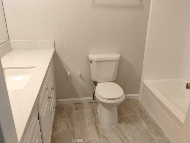 bathroom featuring vanity, a tub to relax in, and toilet