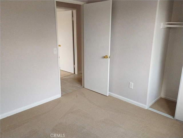 unfurnished bedroom featuring light colored carpet and a closet