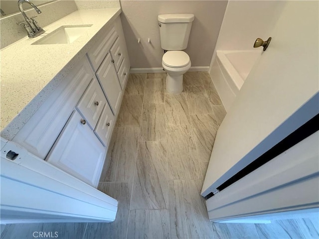 bathroom featuring vanity, toilet, and a washtub