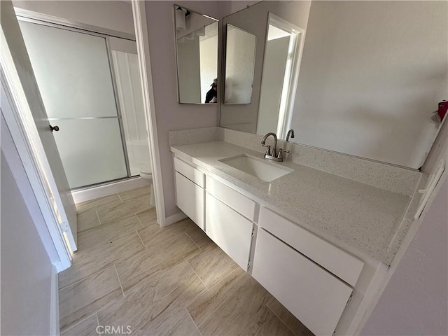 bathroom with vanity, a shower with door, and toilet