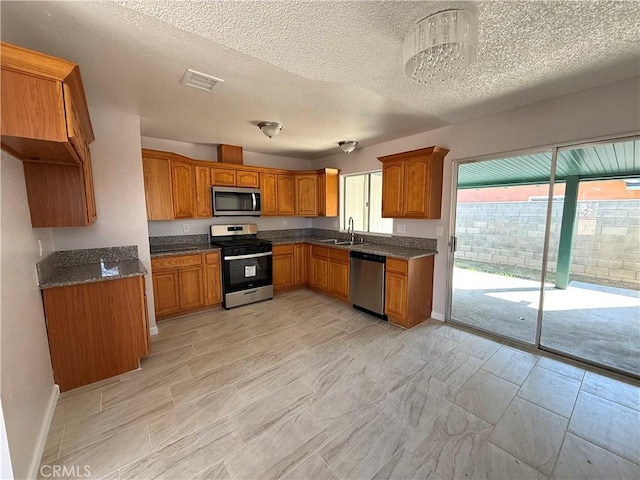 kitchen with dark stone countertops, sink, a textured ceiling, and appliances with stainless steel finishes