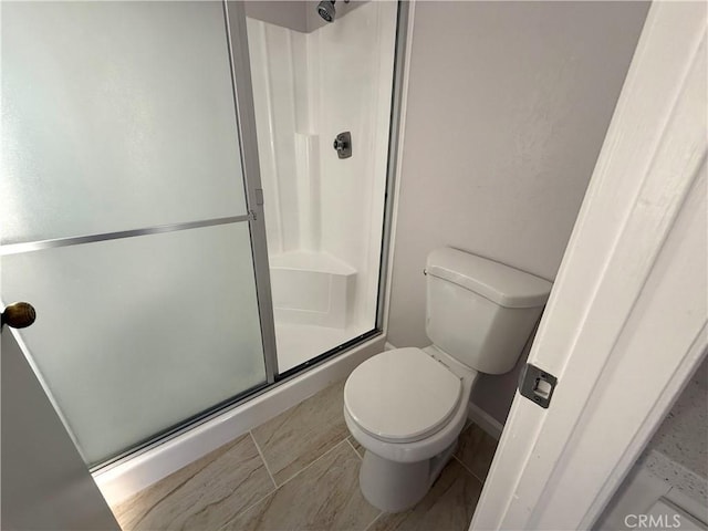 bathroom featuring toilet and a shower with door