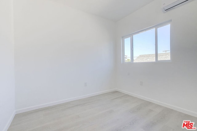 unfurnished room featuring light wood-type flooring and a wall unit AC