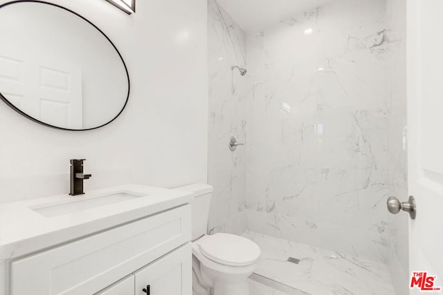 bathroom featuring vanity, toilet, and tiled shower