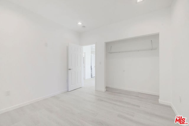 unfurnished bedroom featuring a closet and light hardwood / wood-style flooring