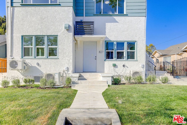 entrance to property featuring ac unit and a lawn