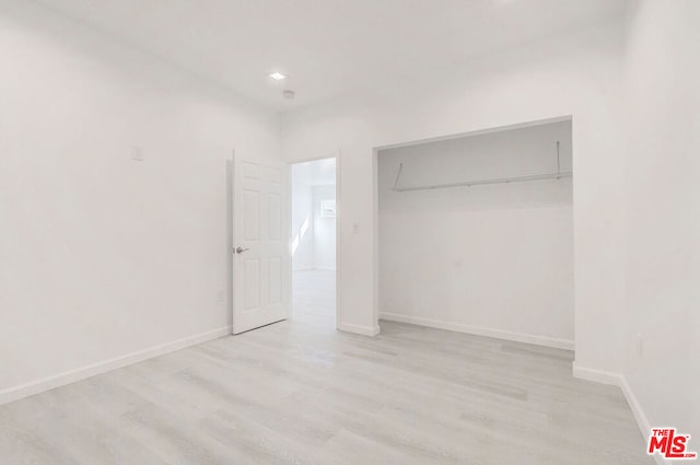 unfurnished bedroom with light hardwood / wood-style flooring and a closet