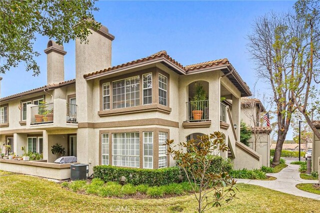 back of property featuring central AC, a balcony, and a lawn