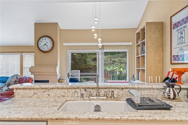 kitchen with hanging light fixtures, a fireplace, and light stone countertops