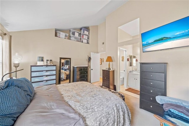 bedroom featuring light carpet, vaulted ceiling, and ensuite bathroom