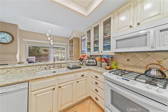 kitchen featuring sink, tasteful backsplash, white appliances, light stone countertops, and cream cabinetry