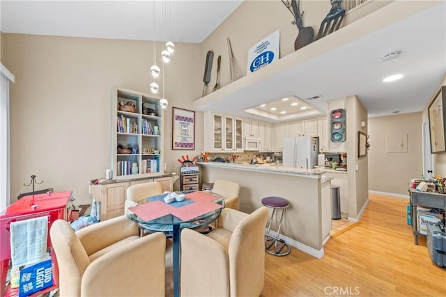 dining space featuring a towering ceiling and light wood-type flooring