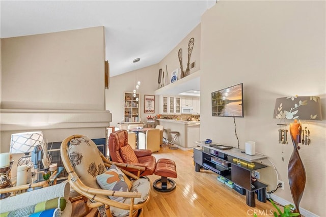 living room featuring high vaulted ceiling and light hardwood / wood-style floors